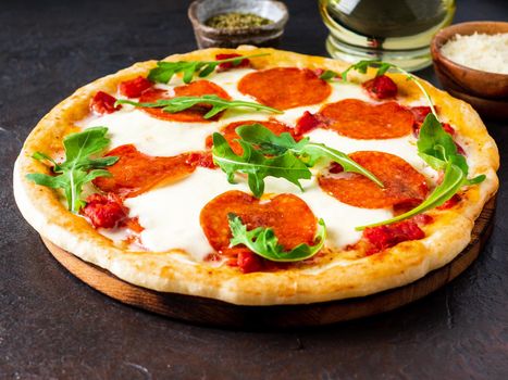 hot homemade Italian pizza margherita with mozzarella and tomatoes on dark brown stone table, side view.