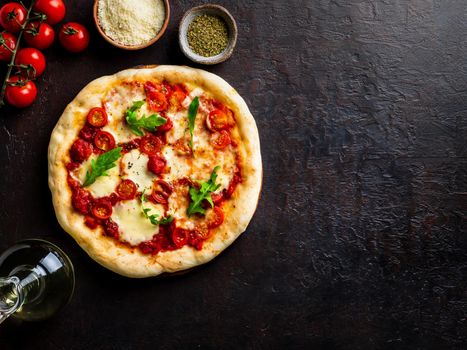 hot homemade Italian pizza margherita with mozzarella and tomatoes on dark brown stone table, top view, copy space.