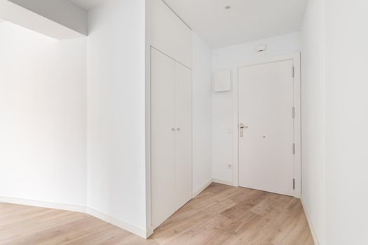 Empty white entrance with white wooden doors and wood flooring