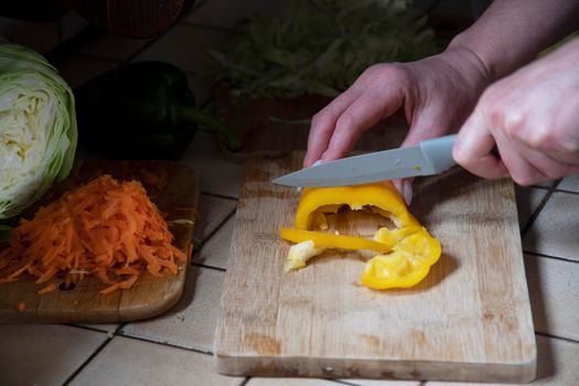 Woman cutting yellow bell pepper at table. High quality photo