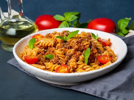 Bolognese pasta. Fusilli with tomato sauce, ground minced beef, basil leaves. Traditional italian cuisine. Side view.