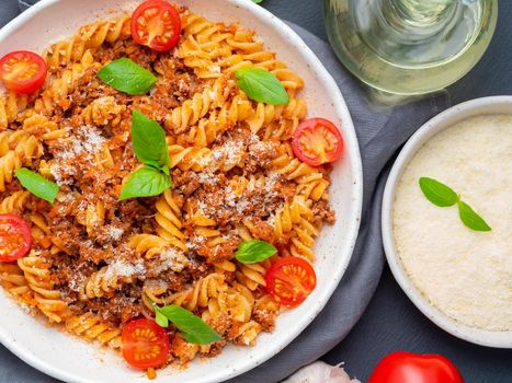 Bolognese pasta. Fusilli with tomato sauce, ground minced beef, basil leaves. Traditional italian cuisine. Top view, close up.