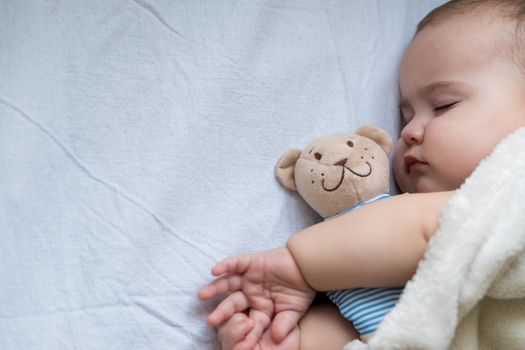 Childhood, care, motherhood, health concepts - Close up Little peace calm infant toddler baby girl sleep resting take deep nap laying hug teddy bear toy on soft warm blanket with close eyes on big bed.