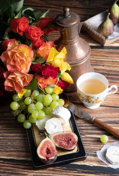 cheese plate with goat cheese, grapes and figs, copper teapot, angle view, healthy food, high-calorie breakfast. High quality photo