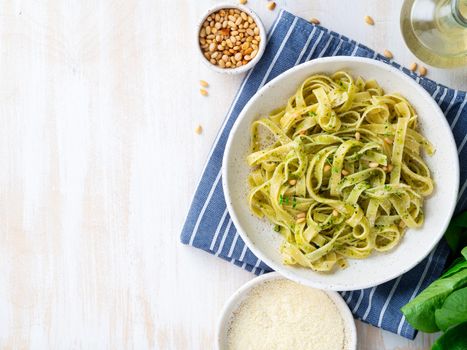 Tagliatelle pasta with pesto sauce made of Basil, garlic, pine nuts, olive oil. Top view, copy space.
