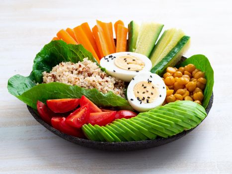 Vegetarian Buddha's bowl, a mix of vegetables. Avocado, quinoa, chickpeas, vegetables, eggs, side view.