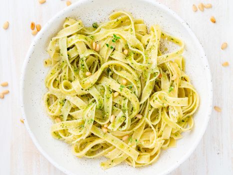 Tagliatelle pasta with pesto sauce made of Basil, garlic, pine nuts, olive oil. Top view, close up.