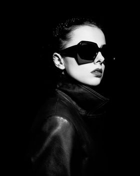 woman in leather coat and sunglasses, black background. High quality photo