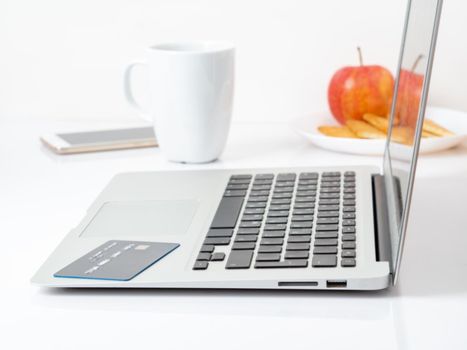 Laptop and credit card, pay for purchases by credit card, online shopping, white background.