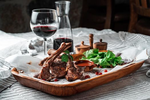 Grilled lamb loin on a wooden plate with lettuce leaves and wine. High quality photo