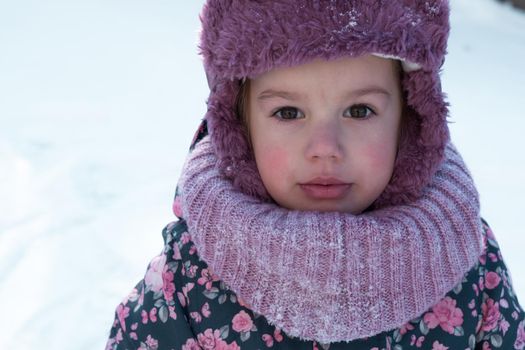 Winter, family, childhood concepts - close-up portrait authentic little preschool minor 3-4 years girl in pink hat look at camera posing smile in snowy frosty weather. happy kid face have fun outdoors.