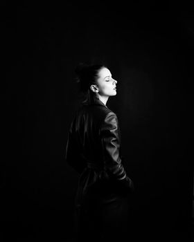 woman with closed eyes in leather coat and, black background. High quality photo