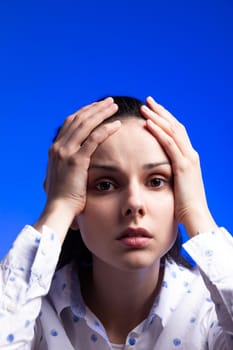 brunette woman in a white shirt with polka dots, on a blue background. High quality photo