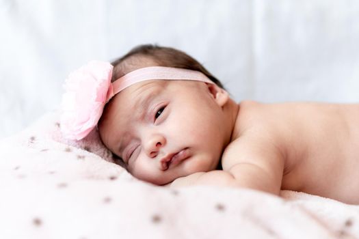 Childhood, care, motherhood, health, medicine, pediatrics concepts - Close up Little peace calm naked infant newborn baby girl in pink hat sleeps resting take deep nap laying on tummy on soft bed.