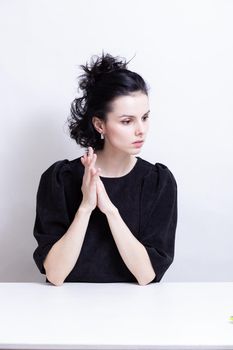 woman with curly hair in a black dress sits at a table. High quality photo