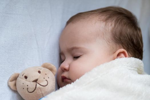 Childhood, care, motherhood, health concepts - Close up Little peace calm infant toddler baby girl sleep resting take deep nap laying hug teddy bear toy on soft warm blanket with close eyes on big bed.