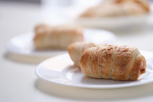 Close-up of homemade sausages in dough on white plate. Freshly baked sausage rolls. Lunch and yummy snack concept