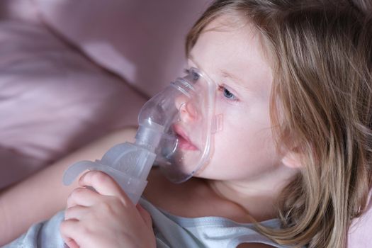 Portrait of sick little child in medical oxygen mask lying in bed. Labored breathing and lack of oxygen or inhalation concept