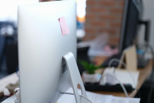 Close-up of computer monitor with sticker on it in office. Modern pc display with paper note, copy space. Digital device