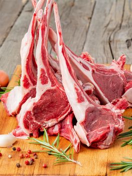 Raw lamb ribs on wooden chopping Board on old rustic wooden background, side view
