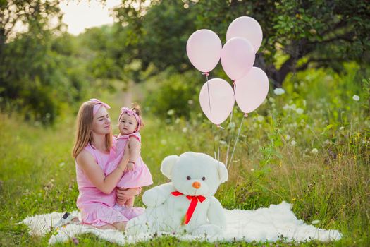 mother and daughter in pink dresses and with pink balloons in nature