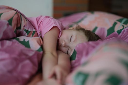 Portrait of little girl kid sleeping sweetly in bed. Daytime sleep. Small child resting after active day. Healthy lifestyle concept