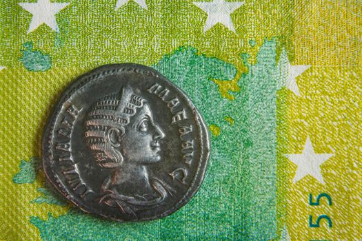 old roman coin lies on euro banknote close up