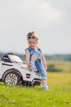 girl in sunglasses stands near the car in nature