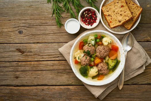 meatballs soup in white plate on old wooden rustic grey table, top view