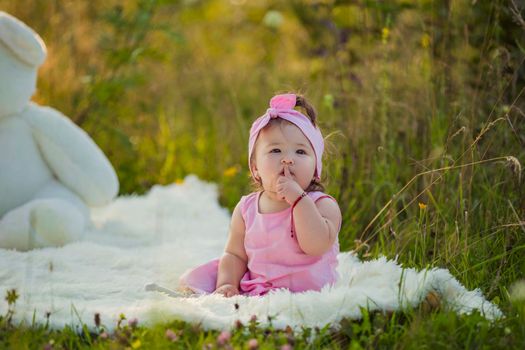 girl in a pink dress sitting on a blanket