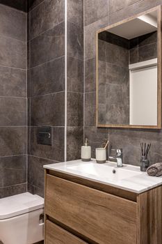 Modern refurbished bathroom with shower zone. Wooden base with white sink and mirror