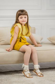 a girl in a yellow suit sits on sofas