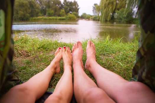 A small camping tent on the lake, a night's lodging and the feet of a young couple.