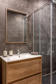 Modern refurbished bathroom with shower zone. Wooden base with white sink and mirror