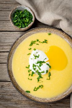 Polenta, porridge with Parmesan cheese and poached egg, vertical on old dark wooden background, top view. traditional Italian cuisine