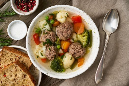 meatballs soup in white plate on old wooden rustic grey table, top view