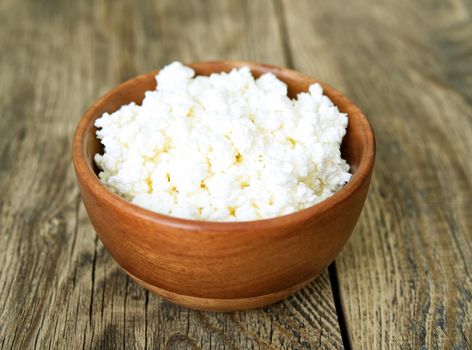 Brown wooden Bowl of homemade curd on a dark brown wooden background, side view, close up