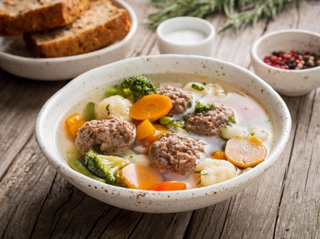 meatballs soup in white plate on old wooden rustic grey table, side view