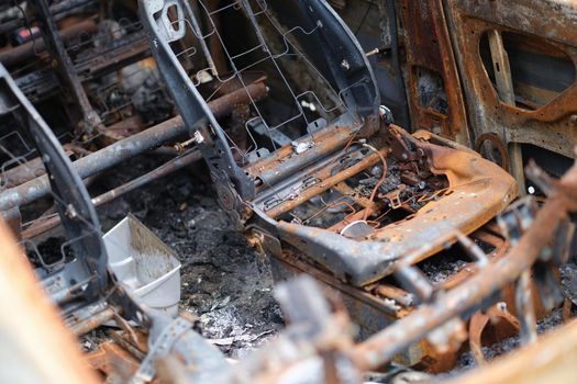 Close-up of car after fire, iron parts of burnt vehicle. Riot, civil protest, hooliganism, criminal in city. Explosion fire result. Car insurance concept