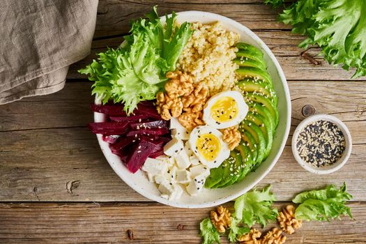 Buddha bowl, balanced food, vegetarian menu. Old wooden dark table, top view. Eggs, avocado, salad lettuce, bulgur, beetroot, tofu.
