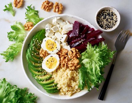 Buddha bowl, balanced food, vegetarian menu. Grey marble table, top view. Eggs, avocado, salad lettuce, bulgur, beetroot, tofu