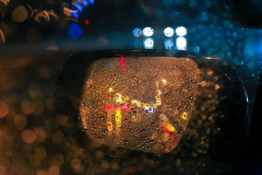 reflection in the car rearview mirror in the rain at night