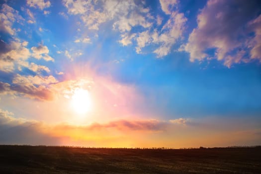 beautiful sunset in cloudy sky over field