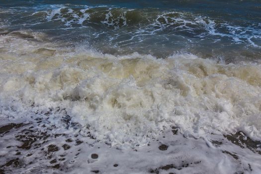 Sea waves splash on the sea shore. Sea foam. Closeup