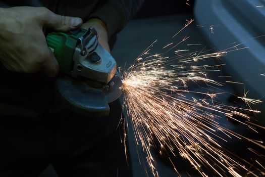 electric grinder in the hands of a man grinding metal