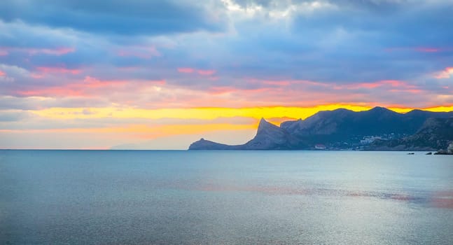 Colorful sunset in the sea bay. Mountainous background.