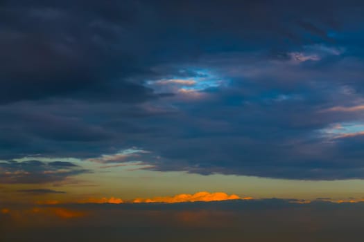 Last ray of the setting sun. Sky covered with dark blue clouds.