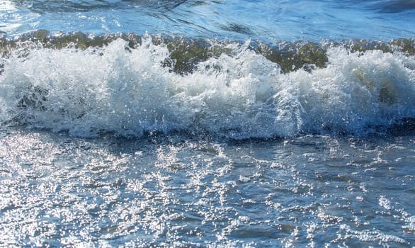 Sea waves roll on to shore. Sea foam. Closeup.