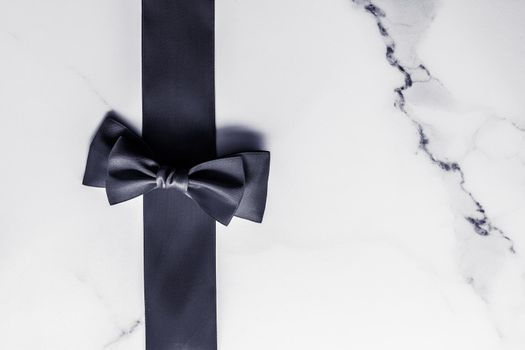 Holiday gift, decoration and sale promotion concept - Black silk ribbon and bow on marble background, flatlay