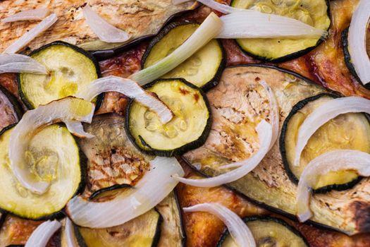 Close-up of pizza topped with grilled eggplant, zucchini and onion. Macro shot of delicious products. Selective focus.